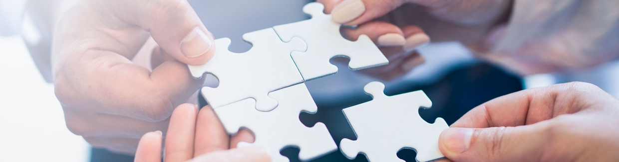 dłonie ludzi składające puzzle