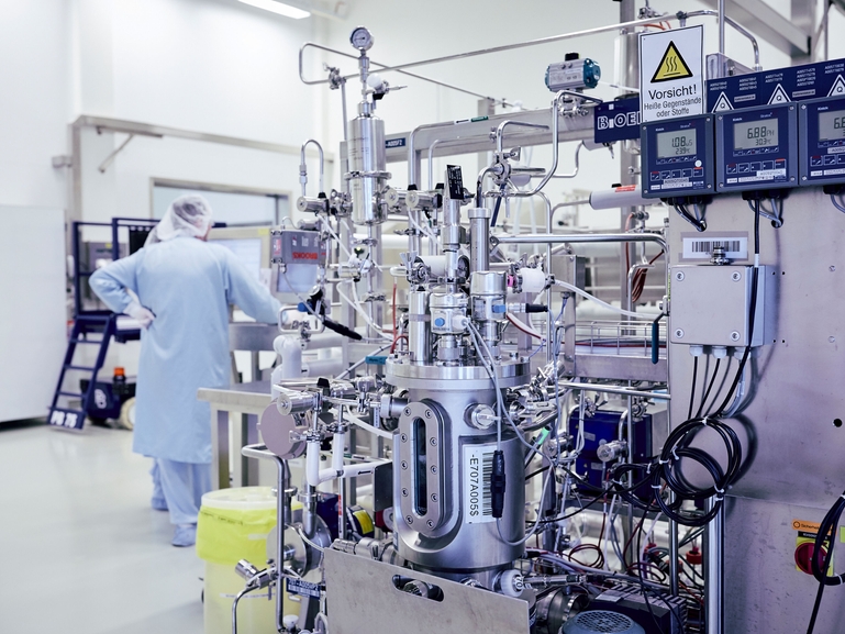 Bioreaktor do procesu fermentacji kultur komórkowych z pracującym przy nim naukowcem Naukowiec obsługujący bioreaktor podczas procesu fermentacji kultur komórkowych dla sektora farmaceutycznego i biomedycznego