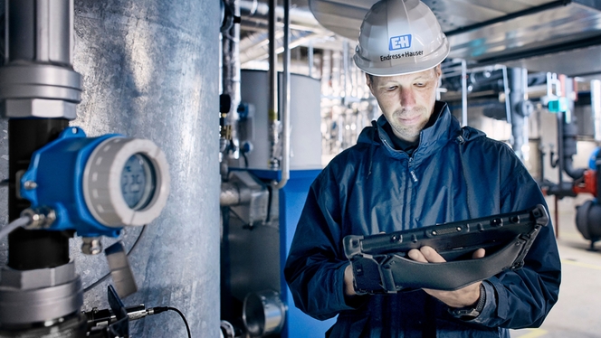 Przetwornik temperatury iTEMPTMT142B obok pracownika Endress+Hauser pracującego na instalacji.