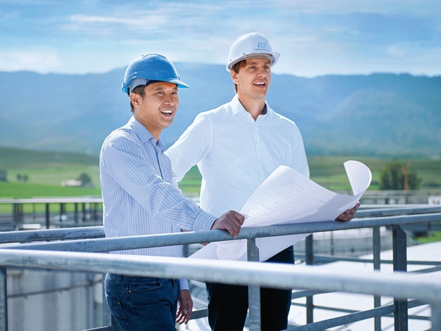 Dwóch inżynierów stojących na szczycie zbiornika magazynowego.